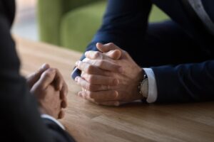 Close-up of two lawyers' hands clasped in negotiation, symbolizing business confrontation.